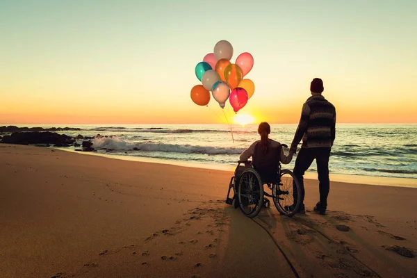 風船を押しながら彼氏と歩いて車椅子の女性 — ストック写真