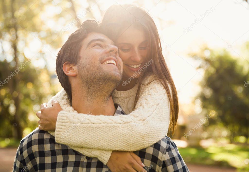 Young couple hugging and smiling in park