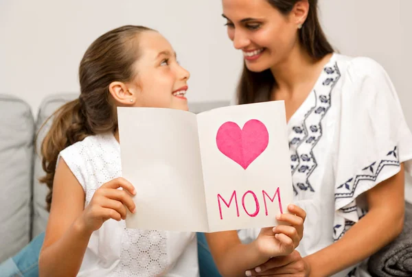 Filha Sentada Com Mãe Sofá Segurando Cartão Sorrindo — Fotografia de Stock