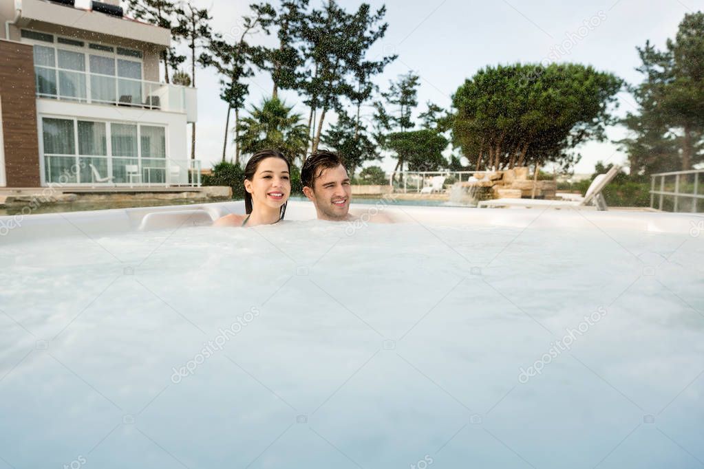 Young couple in luxury hotel inside jacuzzi in rainy day 