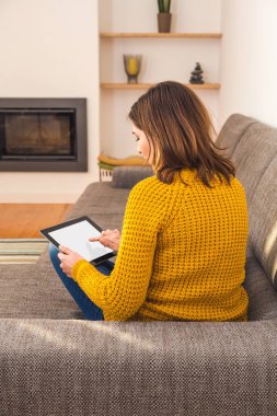 Evde tabletle çalışan güzel bir genç kadın.
