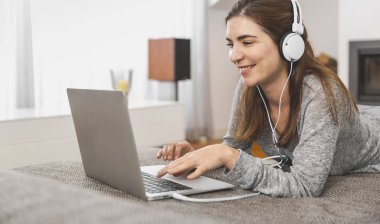 Müzik dinlerken evde dizüstü bilgisayarla çalışan bir kadın.
