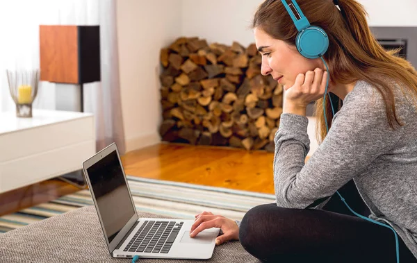 在家里一边听音乐一边用笔记本电脑工作的女人 — 图库照片