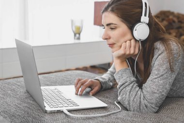 Müzik dinlerken evde dizüstü bilgisayarla çalışan bir kadın.