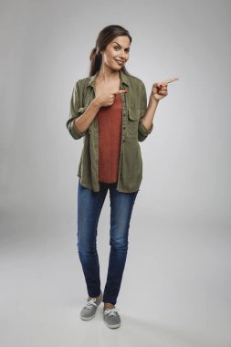 Gri arka planda güzel bir kadın sol tarafını işaret ediyor.