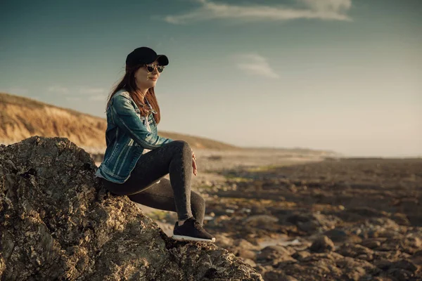 岩の上に座っているビーチで一人で美しい女性 — ストック写真