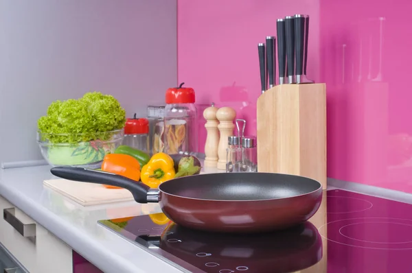 在现代的黑色感应炉上烤锅 在厨房内部的炉顶上烤锅 新鲜蔬菜躺在一张灰色桌子的后面 — 图库照片