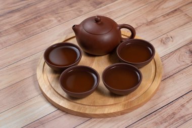 Ahşap tezgahta kil çay fincanı ile kil çay demliği.