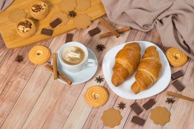 Üst düzey kahve, kruvasan, zencefilli kurabiye, çikolata ve ahşap arka planda tarçın. Metin için boşluk