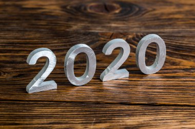 Koyu kahverengi ahşap arka planda seçici odaklı beyaz metal parmaklı bir 2020 numara.