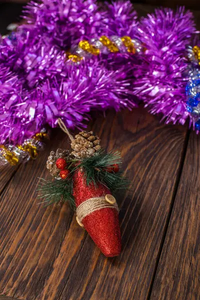 En jul träd leksak och lila tinsel på brunt trä bakgrund — Stockfoto