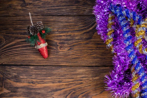 Jul tinsel och röd leksak på bakgrunden av en gammal brun trä bord. — Stockfoto