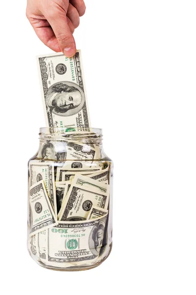 Beyaz arka planda izole edilmiş cam bir kavanozdan 100 Amerikan doları banknotları alan bir el. — Stok fotoğraf