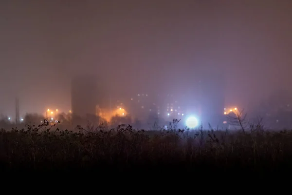 雾蒙蒙的夜晚前的干枯的黑暗的草场，压抑的郊区贫民窟 — 图库照片