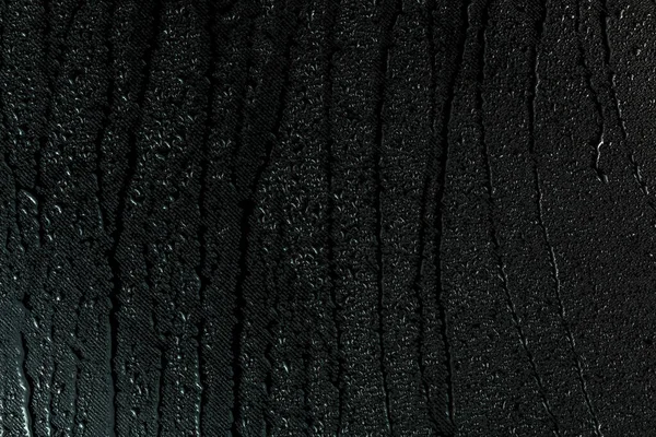 Water drops on flat black rubber surface macro background with smudges — Stock Photo, Image