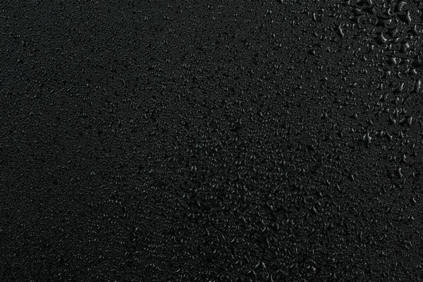 Тёмный абстрактный фон капель воды на плоской чёрной резиновой поверхности — стоковое фото