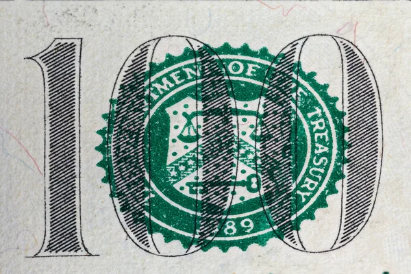 Un nombre de cent sur un billet de dollar et le symbole du département du Trésor des États-Unis en macro grossissement — Photo