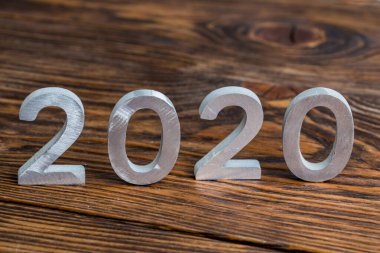Koyu kahverengi ahşap arka planda seçici odaklı beyaz metal parmaklı bir 2020 numara.