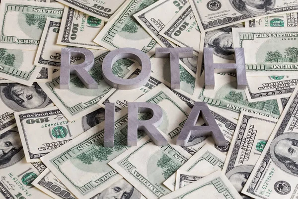 The words ROTH IRA laid with aluminium letters on the US dollar banknotes background - with selective focus