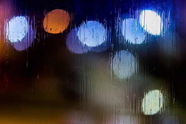 Un fondo abstracto luces de la calle noche bokeh a través de vidrio húmedo, primer plano con enfoque selectivo —  Fotos de Stock