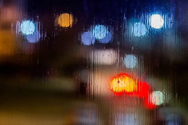 Ein abstrakter Hintergrund Nacht Straßenbeleuchtung bokeh durch nasses Glas, Nahaufnahme mit selektivem Fokus — Stockfoto