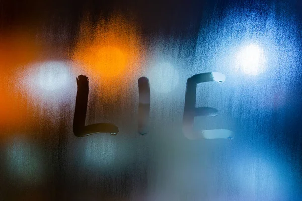 Слово ложь, написанное на ночном мокром оконном стекле крупным планом на фоне боке — стоковое фото