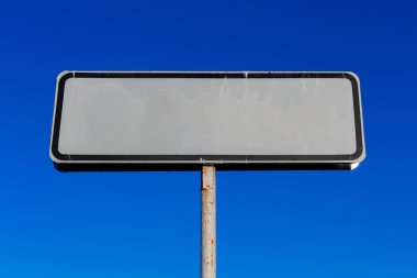 Mavi gökyüzü arka planında küçük beyaz yol işareti