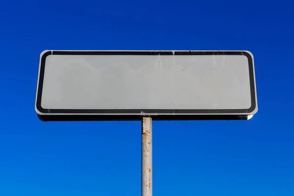 Mavi gökyüzü arka planında küçük beyaz yol işareti — Stok fotoğraf
