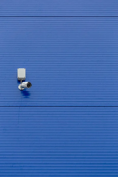 大規模な青鋼サイロの壁に小さな白いセキュリティカメラ — ストック写真