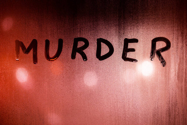 the word murder handwritten on wet glass of night window with bloody red back light of street lights
