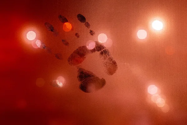 Handprint on night wet glass in red colors with blurry street light in backround — ストック写真