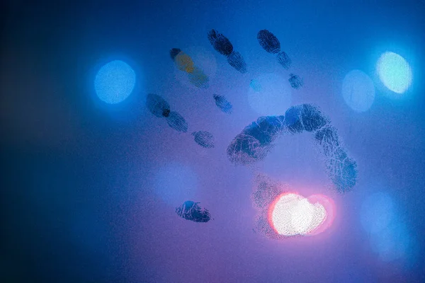 Impronta a mano su vetro bagnato notte in colori blu freddo con lampione sfocato nel backround — Foto Stock