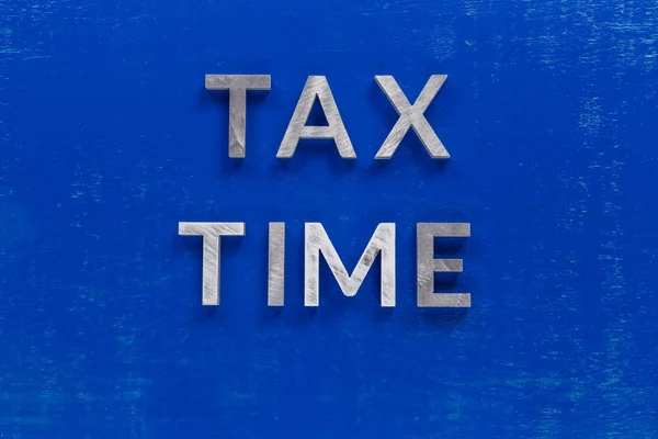 Slova daňový čas layed na modré malované desky s tlustou stříbrnou kovovou afabetu znaky — Stock fotografie