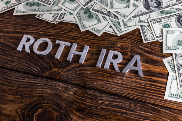 Words ROTH IRA laid on wooden surface with metal letters and us dollar banknotes — Stock Photo, Image