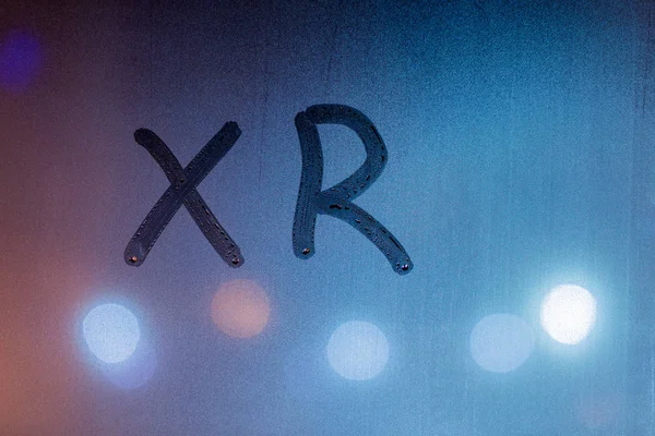 An abbreviation xr for extended reality handwritten on blue night wet window glass — Stock Photo, Image