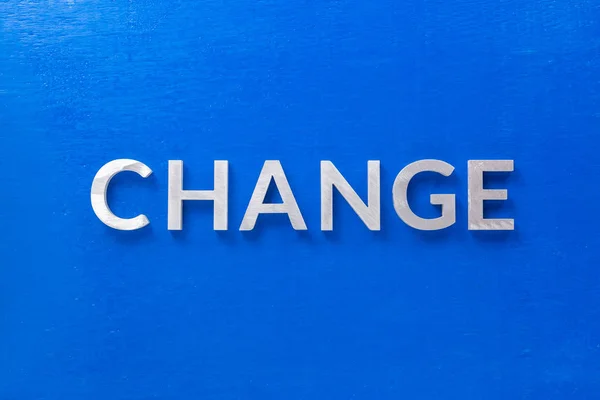 The word change laid with silver metal characters on blue painted wooden board in flat lay with central composition — Stock Photo, Image