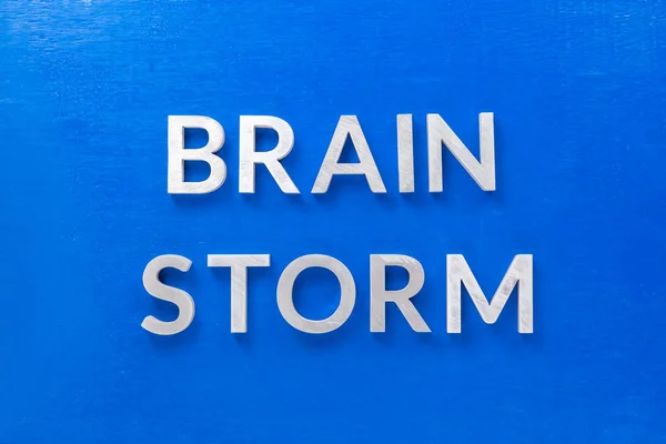 the phrase brain storm laid with silver metal letters on blue board in flat lay with central composition