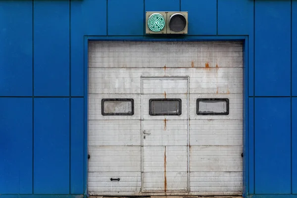 En vit automatisk uppåtgående skjutport på blått garage med grönt belyst trafikljus — Stockfoto