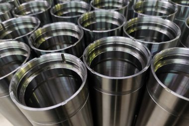 a close-up shot of shiny steel aerospace cnc turned tubes in a batch with selective focus and background blur