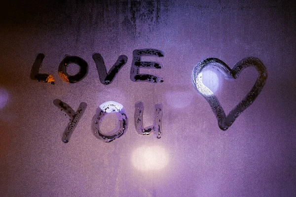 Слова любові, які ви написали на туманному склі нічного вікна та символі серця — стокове фото