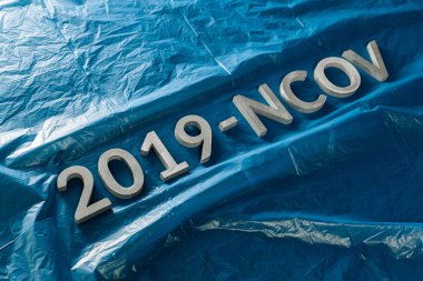 The word 2019-NCOV laid with metal letters on crumpled classic blue plastic film background in slanted diagonal composition