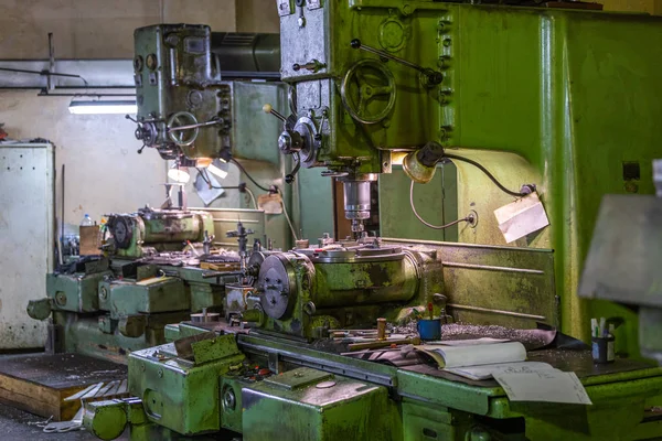Two old and big soviet vertical 5-axis industrial milling and boring machines indoors with selective focus and blur.