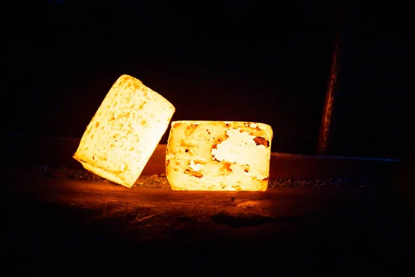 Um par de peças cilíndricas brilhantes quentes pesadas prontas para forjar no fundo de metal escuro — Fotografia de Stock