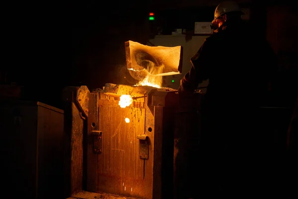 排気フード付きの冶金炉からスラグを除去する作業員と蒸気付きの溶解金属 — ストック写真