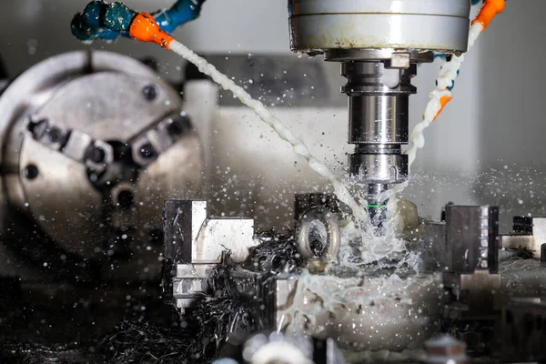 Ein Prozess des vertikalen CNC-Stahlfräsens mit externen Wasserkühlwasserströmen, Spritzern und vielen Metallsplittern — Stockfoto