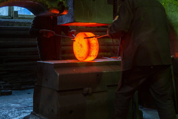 close-up picture of hot steel manual forging process with big mechanical hammer machine