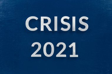the words crisis 2021 laid with silver metal letters on blue surface for stock market background
