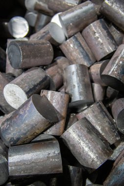 a pile of raw steel short rods cutted by saw - workpieces prepaired for forging, close-up with selective focus