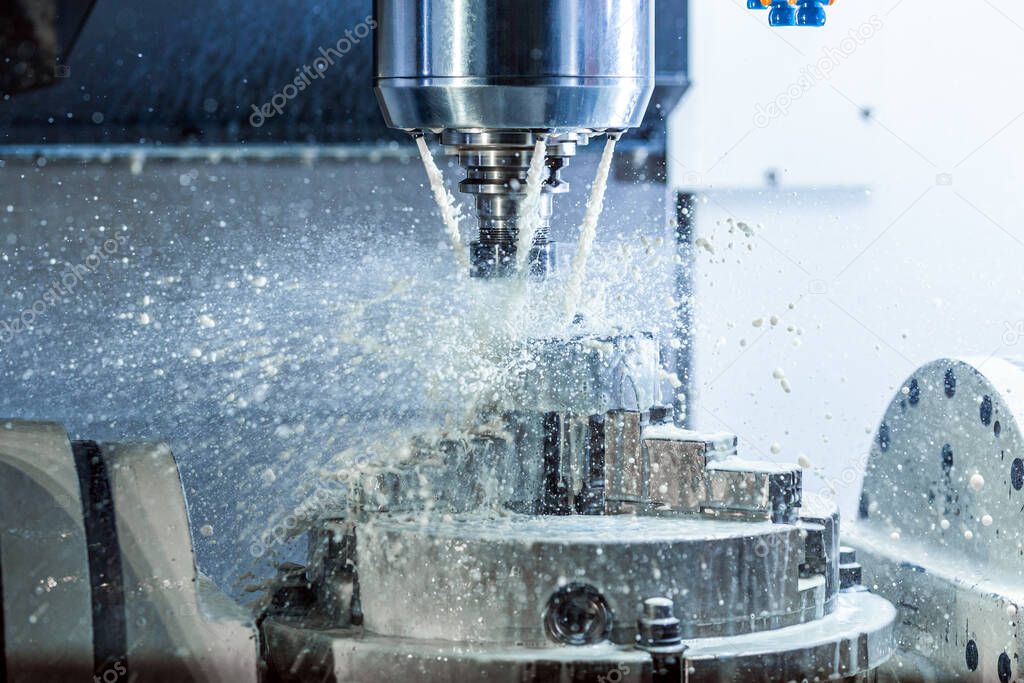 Vertical photo of industrial wet milling process in 5-axis cnc machine with coolant flow under pressure and freezed splashes.