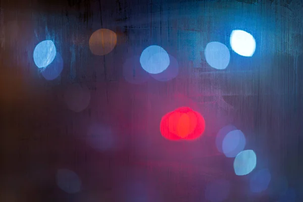 一个抽象的背景，红色和蓝色的灯在夜间的特写中，有选择性的聚焦，经过湿透的玻璃窗 — 图库照片